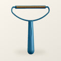 Teal fabric scraper with a brass blade, on a warm cream background